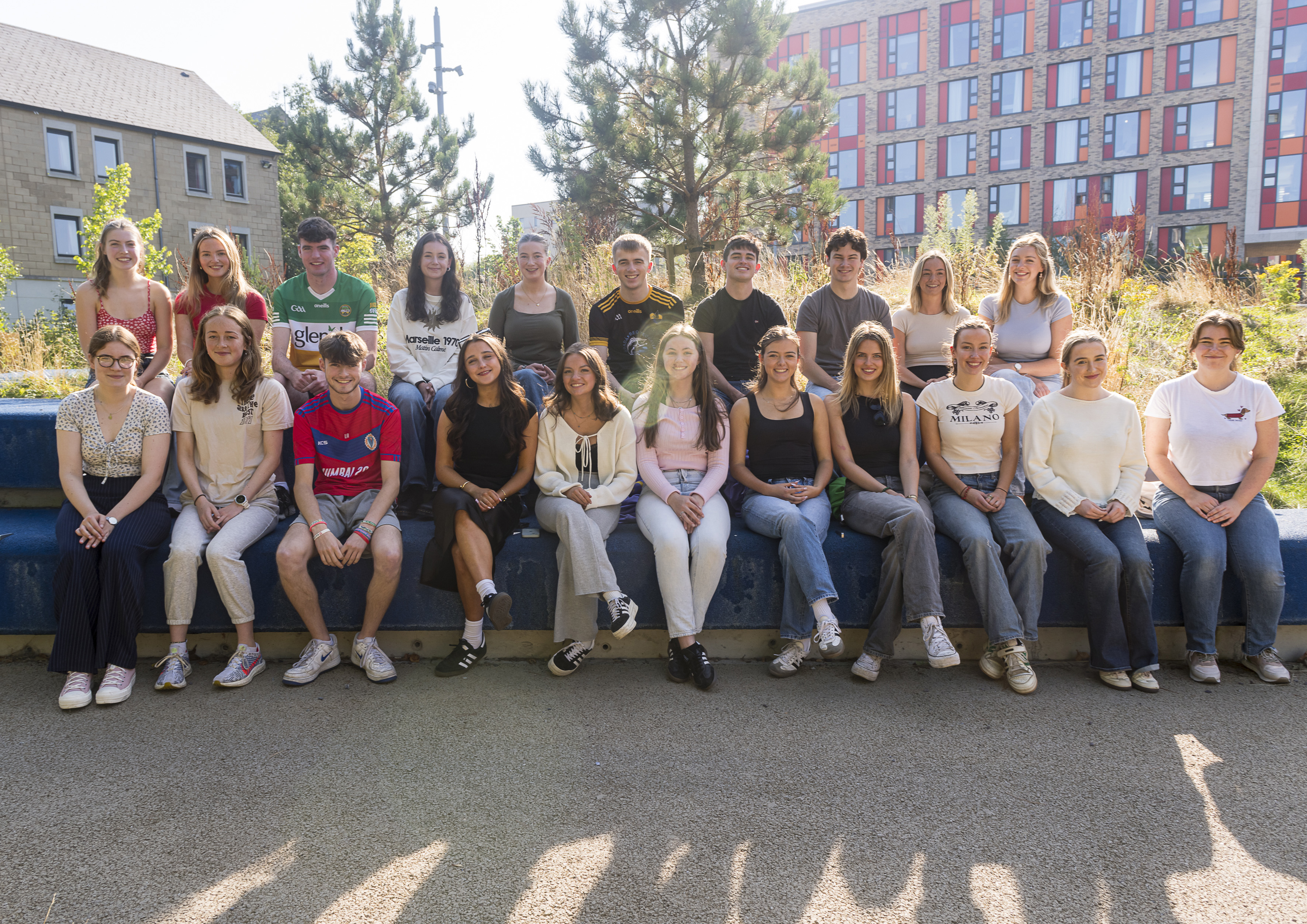 Gaeltacht UCD's scholarship recipients for the year 2024-2025 sitting together outside on a sunny day.