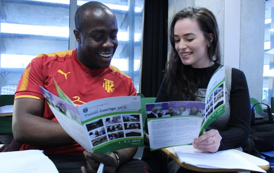 Two students reading the Gaeltacht UCD Pamphlet