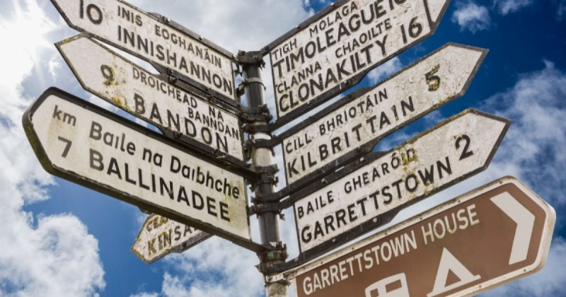 A sign post with multiple signs showing English/Irish pointing in different directions