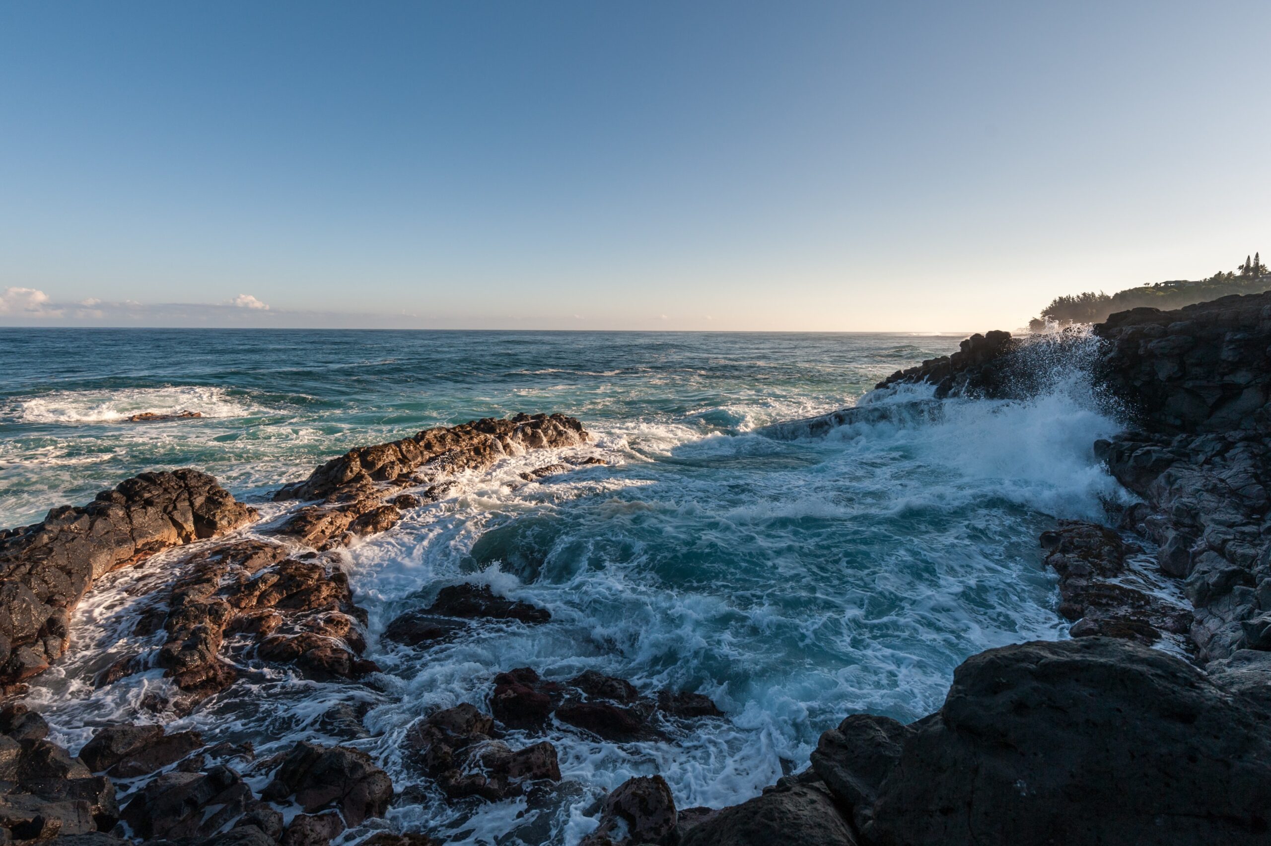 Ocean waves splashing on a rocky coast at Queens Bath. Photo by Sergei Akulich