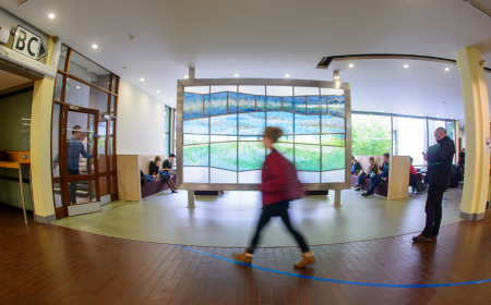 Blurred image of a person in red walking past stained art window in Newman