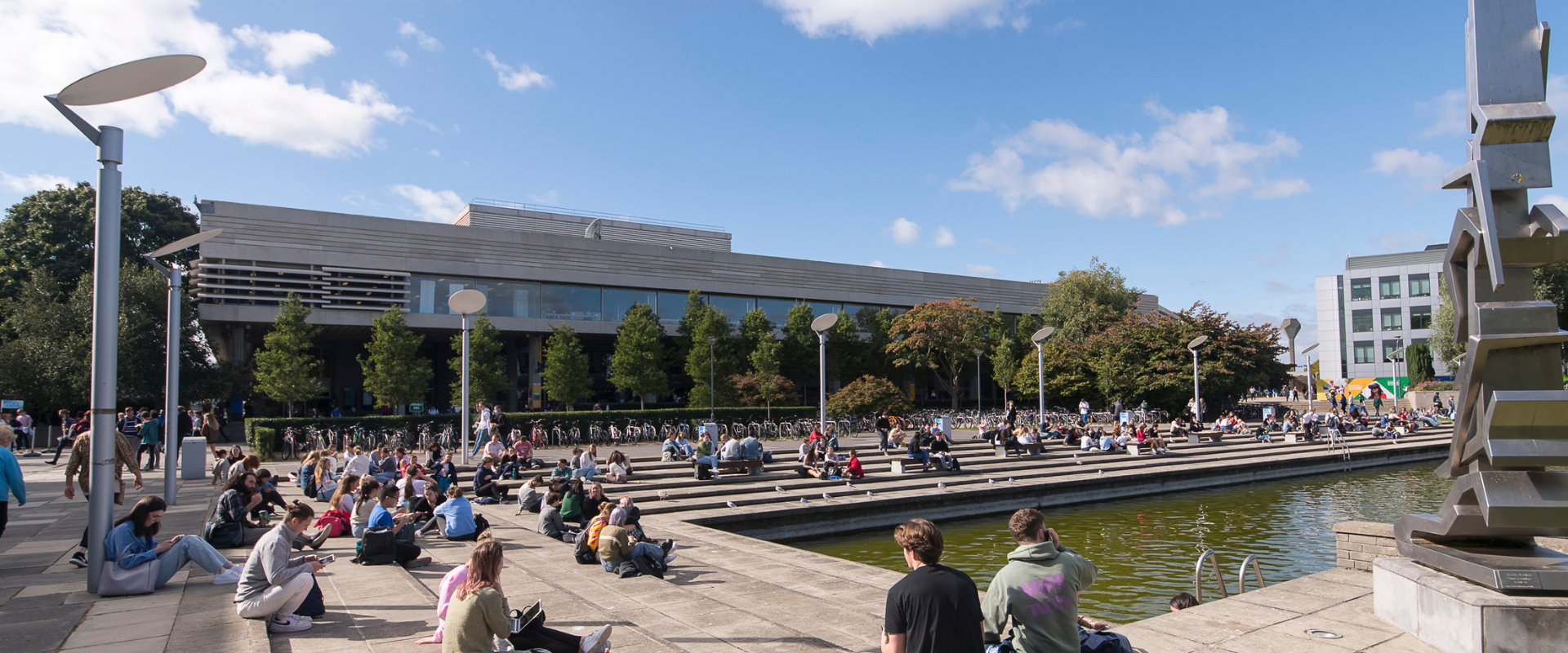 Students sitting around UCD lake on a sunny day