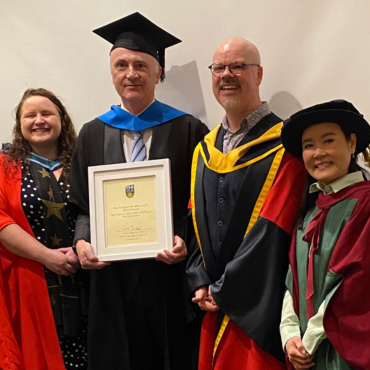 Graduate in cap with two female and one male academic