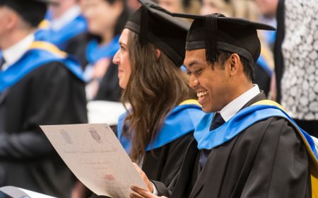 UCD graduate smiling while looking at degree