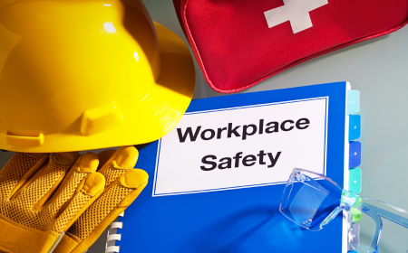 Workplace Safety manual with safety gloves, first aid kit and yellow hard hat