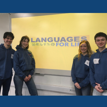 Four students in front of the Languages for Life logo