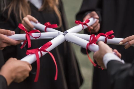 Group of graduates holding their scrolls together in a circle